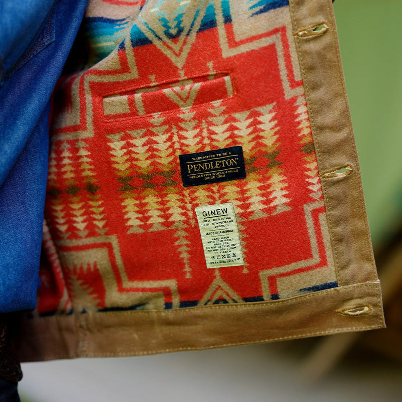 Close-up of a Pendleton coat worn outdoors, showing the tan woolen lining with a red, blue, and beige geometric pattern and a visible Pendleton label.